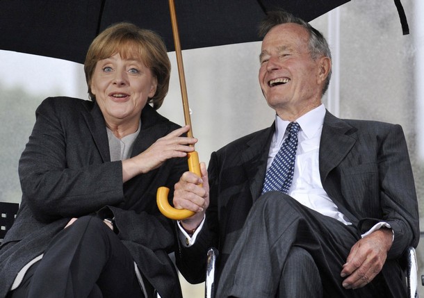 German Chancellor Angela Merkel (L) BRIBED to keep secret George Herbert Walker Bush's (Bush41) STOLEN U.S. Treasury funds hidden in secret accounts at the Deutsche Bank  AFP/Getty